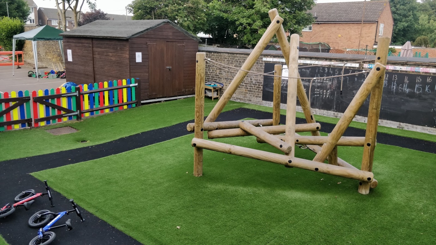 Photo showing an outdoor play area on the Dartford Primary Academy grounds, with a wooden climbing frame seen.