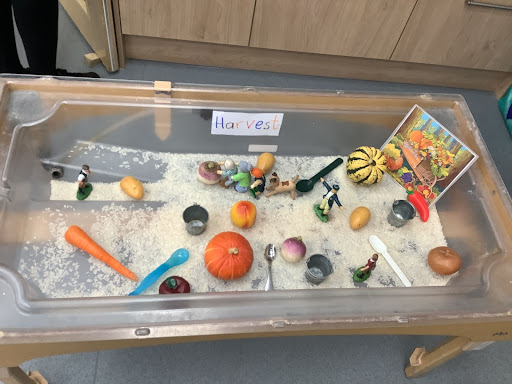 Sandbox with toys and vegetables in it