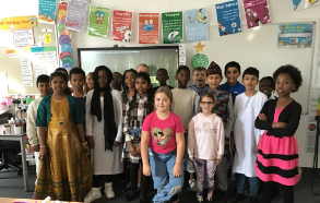 A class of pupils are seen gathered together at the front of their classroom to show off their fancy dress outfits for the camera.