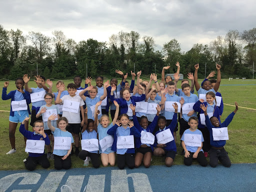 A large group of pupils are seen smiling and waving at the camera whilst competing in the Dartford District Athletics competition.