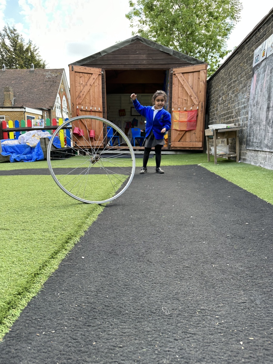 A child pushing a hula hoop across the ground