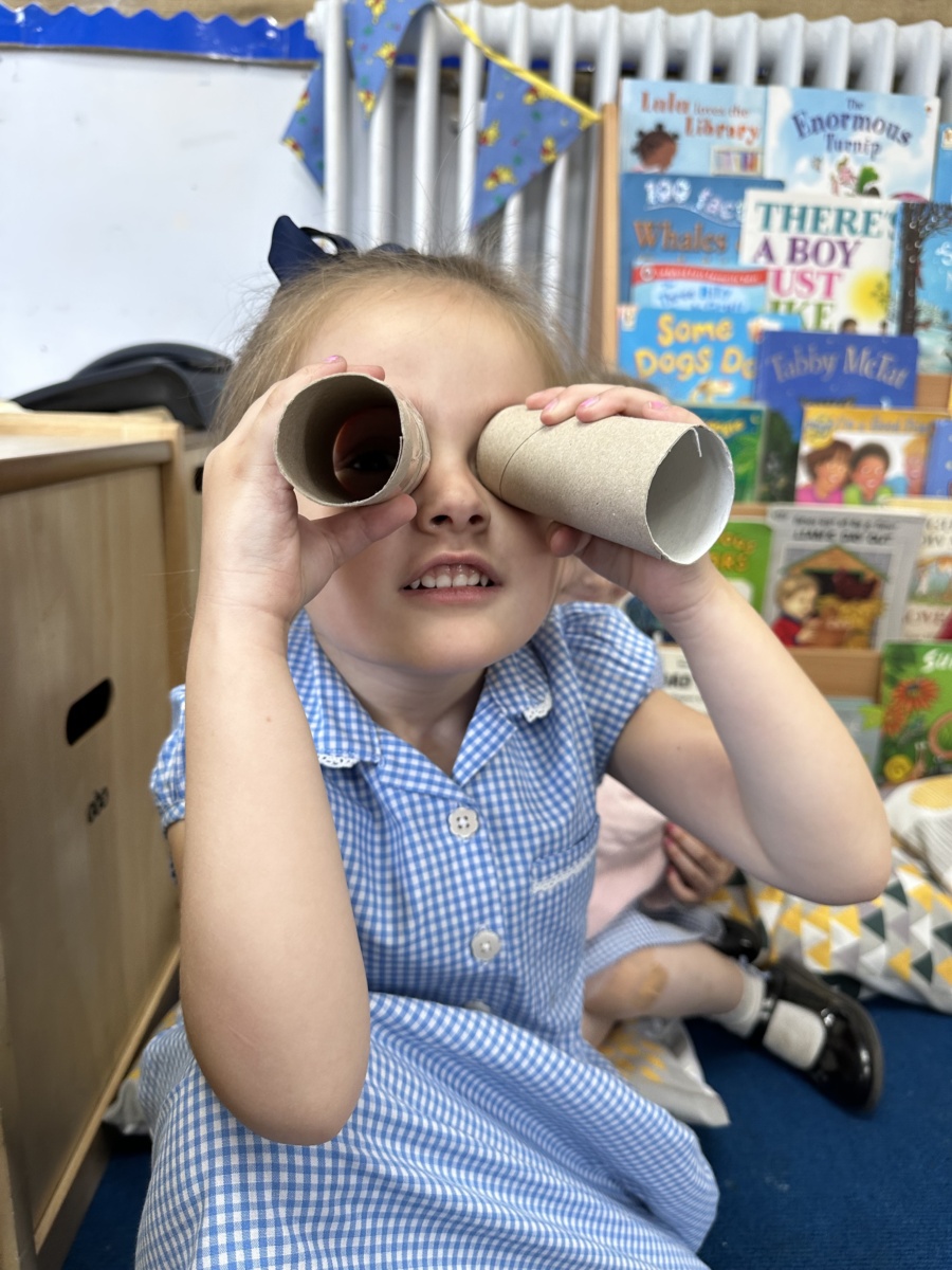A child holding toilet roll tubes up to her eyes like a pair of binoculars.
