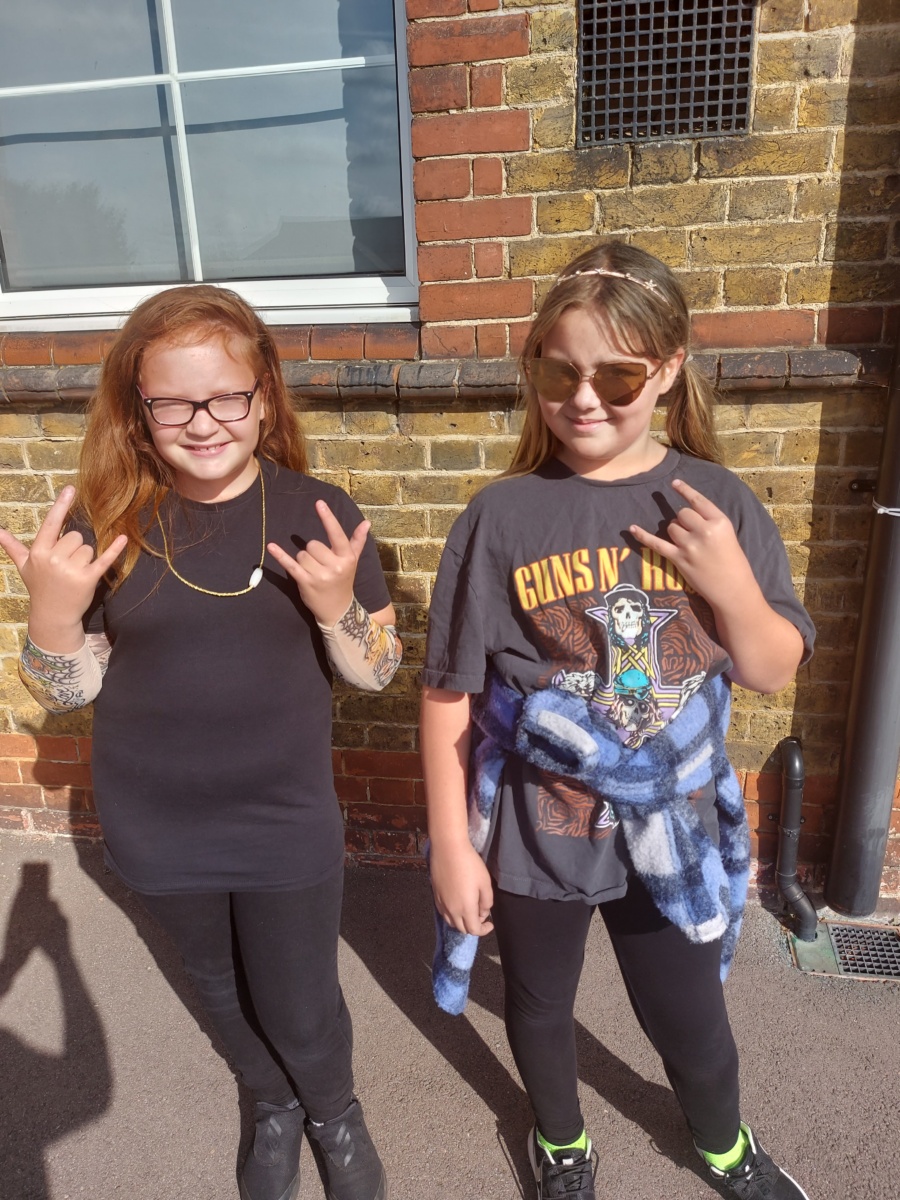 Two girls are seen dressed up as rockstars and posing for the camera.