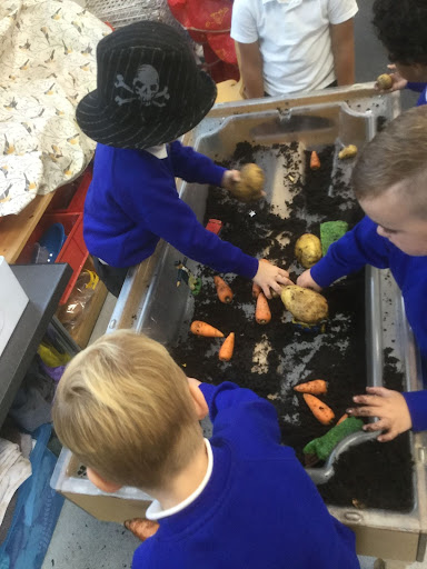 Nursery pupils are seen learning about Harvest and Farming by playing with some toys in a tray of soil.