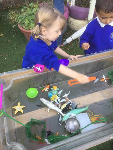Two Nursery pupils can be seen playing with some toys in a tub of water. Inspired by the story of 'The Rainbow Fish'.