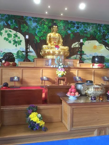A photo showing the inside of a Buddhist Temple taken during a school trip. A golden statuette of a Buddha can be seen positioned at the front of the room.