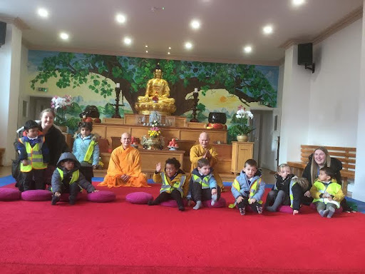 Some young pupils are pictured sat on the floor, alongside their teachers, inside a Buddhist Temple during a school trip.