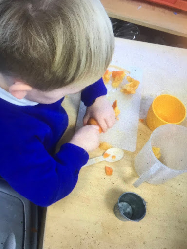 A young boy from Nursery is shown picking up some sliced Oranges in order to make Orange Juice.