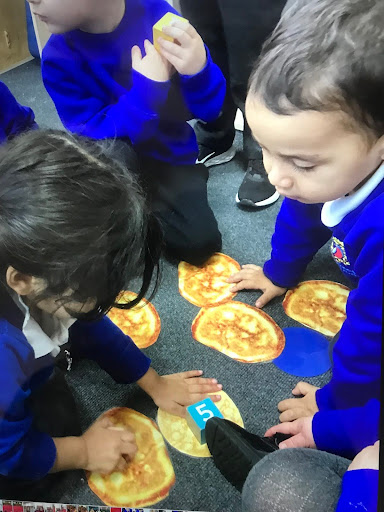 A small group of Nursery children are pictured sitting on the floor, about to eat some Chapattis.
