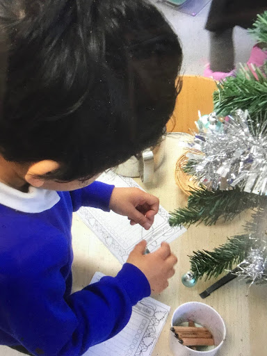 A young boy from Nursery is pictured decorating a Christmas Tree in his classroom.