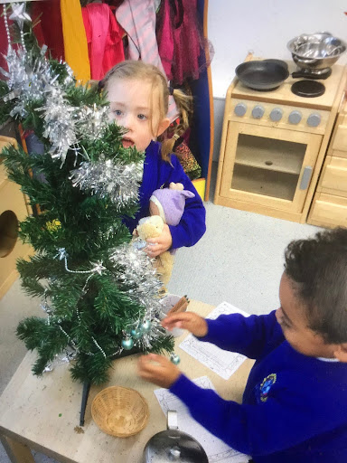 Two Nursery pupils, a boy and a girl, are seen decorating the Christmas Tree in their classroom together.
