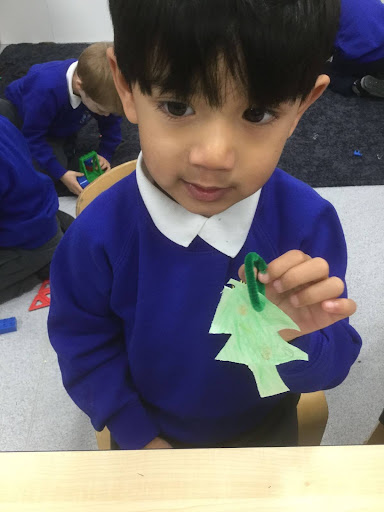 A young boy from Nursery is pictured holding up a Christmas Tree decoration he has made himself.