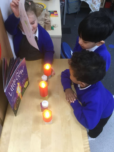 Three Nursery pupils are seen observing the light made from some battery candles. They learned about the importance of fire safety.