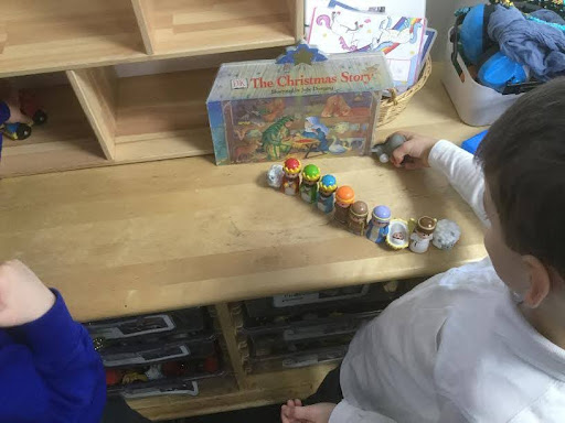 A child from Nursery is shown playing with some figurines of characters from the Nativity story.