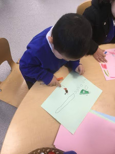 A young boy from Nursery is seen drawing a picture of his time spent at home during the Christmas holidays.