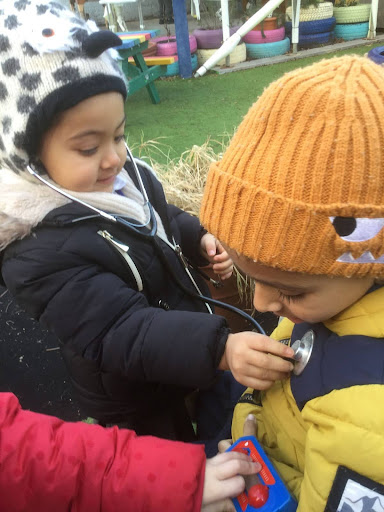 Two young Nursery pupils are pictured playing together with a stethoscope, as part of their learning about 'Real Superheroes'.