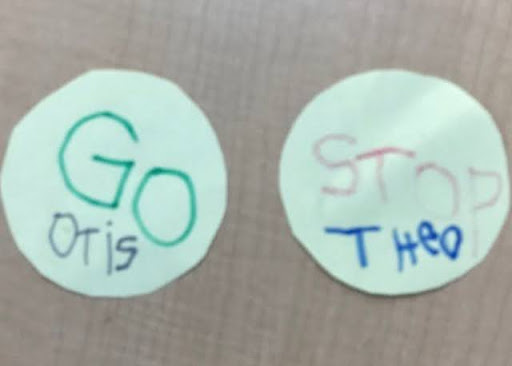 A photo showing two circular pieces of paper with the words 'GO' and 'STOP' written on them by Nursery pupils, imitating road traffic signs.