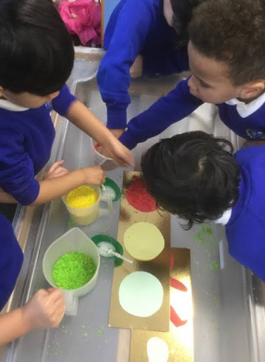A small group of boys from Nursery are pictured working together to create their own traffic light, using different coloured paints.