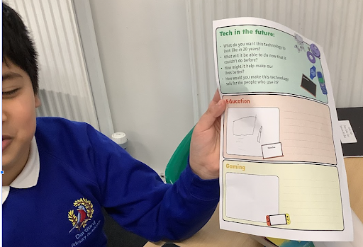 A young boy in academy uniform is pictured smiling and holding up a worksheet he has completed for Safer Internet Day 2024.