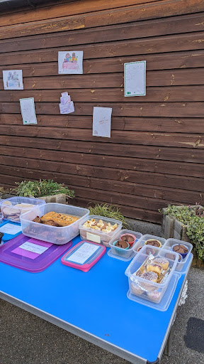 A photo showing some cakes made by Reception class laid out on a table outdoors, ready to be sold at a bake sale.