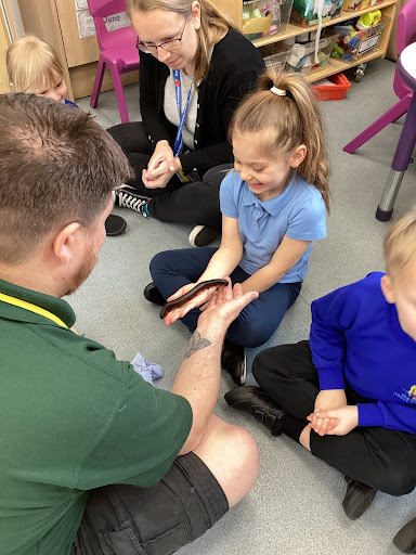 A young girl from Reception Class can be seen smiling, whilst holding an African Millipede in her hands. The creature was brought in by the company Exotic Explorers during a visit to the academy.