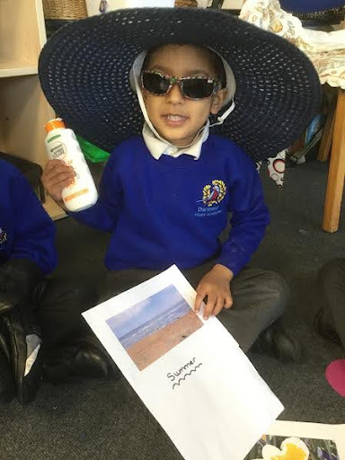 A young Nursery pupil is seen smiling for the camera, whilst wearing a Sombrero hat and holding a bottle of suncream in his hand.