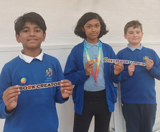 Three DPA students are pictured standing alongside one another in their academy uniform, smiling and holding banners with the words 'Book Creator' on them.
