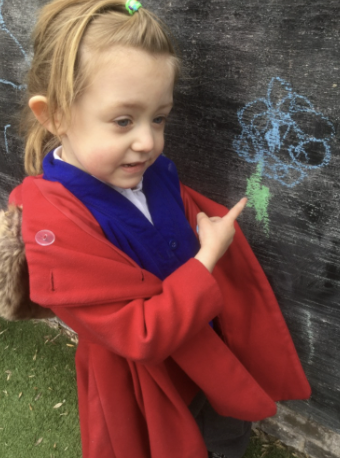 Child pointing to a chalk drawing of a flower