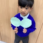 A young boy from Nursery is pictured smiling for the camera, whilst holding up two road safety signs she has created in class.